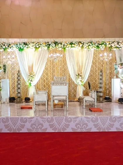 An elegant stage for a sophisticated wedding. The backdrop features a golden lattice screen and soft cream drapes, accented with traditional silver tiered lamps, creating a look of timeless grace.