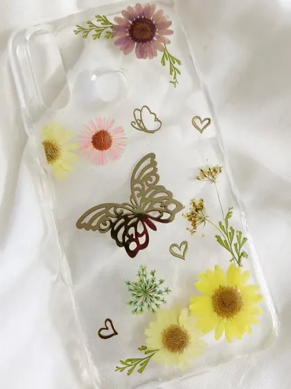 This resin phone case is extra special, with a delicate butterfly charm embedded among the pressed flowers. It's a perfect example of how we can personalize your accessories.