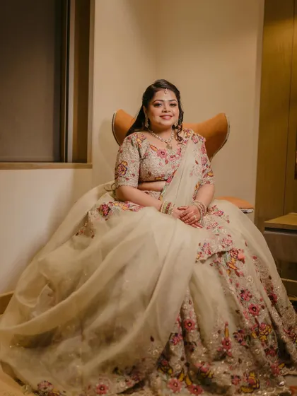 A beautiful portrait of the bride seated in a chair, her voluminous floral lehenga spread out around her. She looks like a princess on her engagement day.