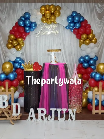 A bold and colorful balloon arch with red, blue, gold, and white balloons. The sequin and tulle pedestals add a unique and fun texture to the setup.