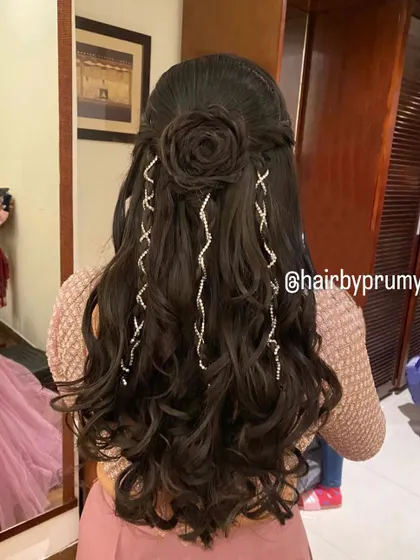Creating magic with this half-up rose bun. The intricate flower shape is crafted from hair, and the sparkling accessories cascade down into voluminous curls.
