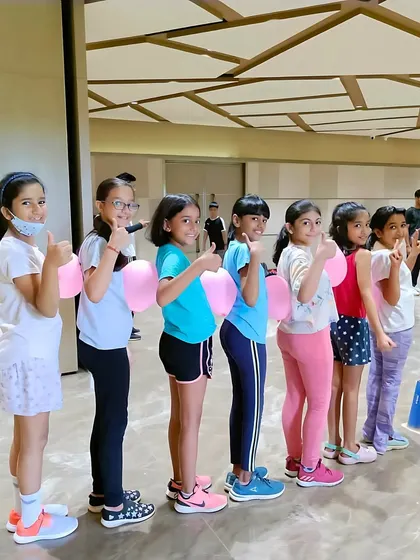 A group of girls gives a thumbs-up during a fun fitness activity with balloons. We believe in making exercise enjoyable to keep our young athletes engaged and motivated.