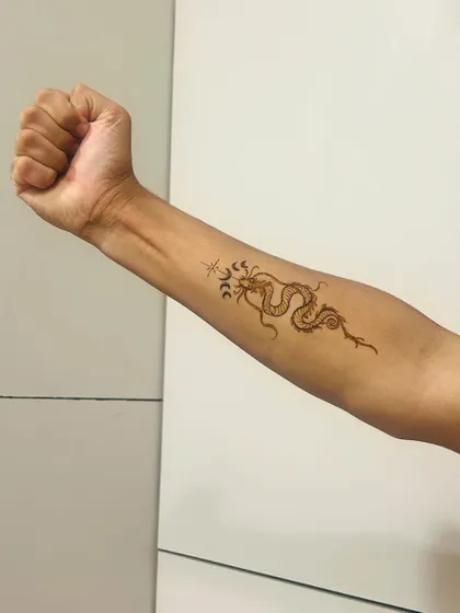 The dragon henna tattoo shown on the full forearm. It's a bold and modern choice.
