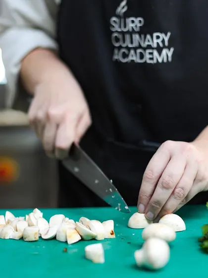 Another shot of a student honing their knife skills. Repetition and practice are essential for building muscle memory and confidence.