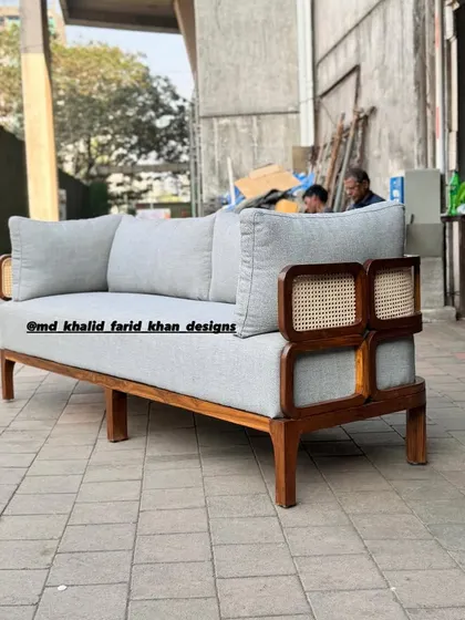 This sofa combines the comfort of plush cushions with the timeless appeal of teak and cane, perfect for a bright living area or hotel lounge.