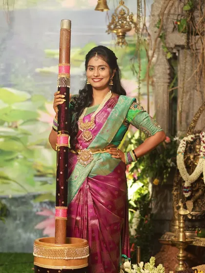 Posing during a traditional ceremony, this client looks stunning. Her magenta and green silk saree is paired with a green blouse that has delicate embroidery work on the sleeves.