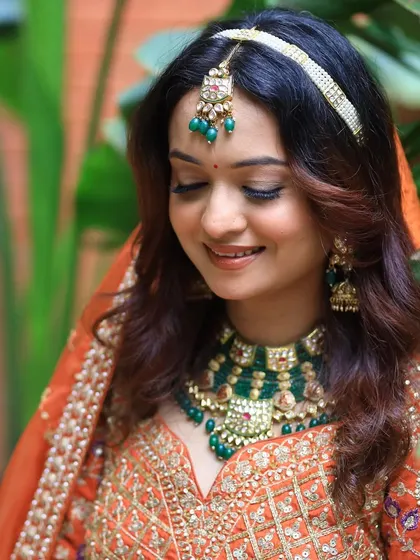 A royal Indian bride look with soft, glowing makeup and a beautiful orange lehenga.