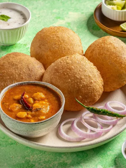A plate of Chole Puri, with fluffy, deep-fried bread served with a spicy chickpea curry and pickled onions.