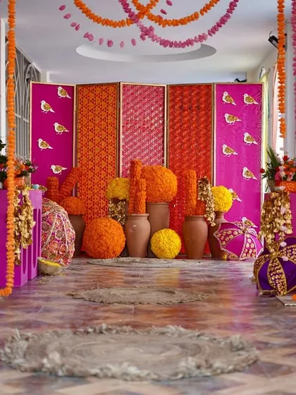 A colorful and sophisticated entrance for a Phulkari-themed Mehendi. We used strings of marigolds and a backdrop of vibrant pink and orange panels with bird motifs to create a joyful welcome.