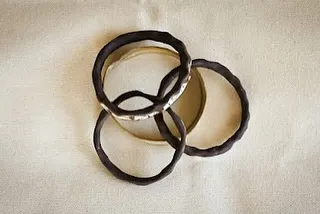 A set of interlocking ceramic bangles with a dark, textured glaze. They make a lovely sound when they move together.