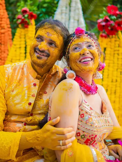 A close-up of the couple, their faces covered in turmeric, sharing a happy and intimate moment during their Haldi.