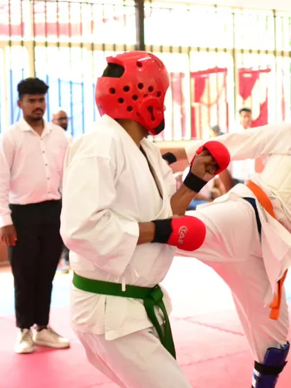 An adult student engages in a sparring match, demonstrating a high kick. Our classes welcome students of all ages, and many adults find success and confidence through our competition coaching.