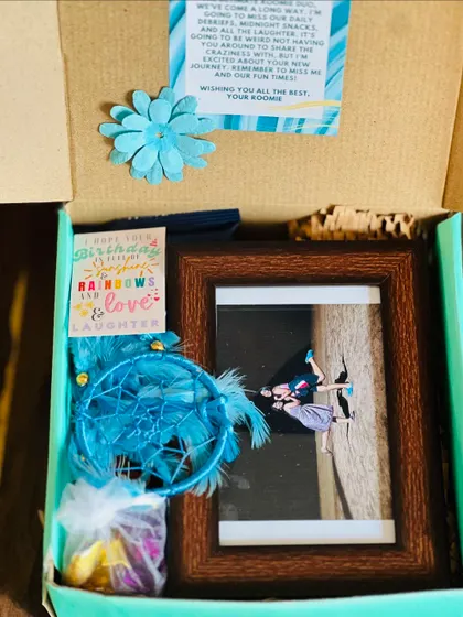 The inside of the roommate farewell box, revealing a personalized photo frame, a dreamcatcher, and a heartfelt note.
