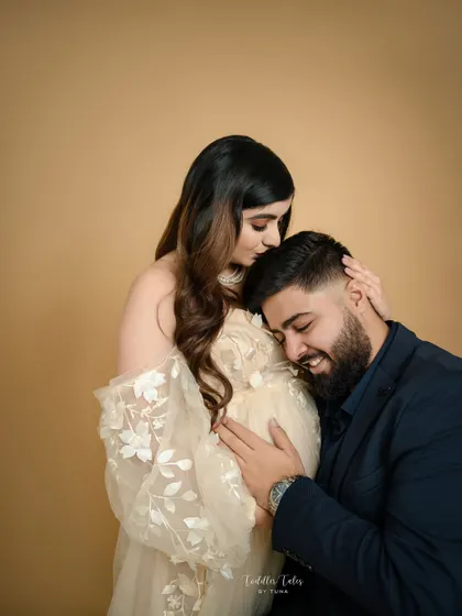 A tender embrace. The father-to-be gently holds the mother and her bump, a beautiful expression of his love and protective instinct.