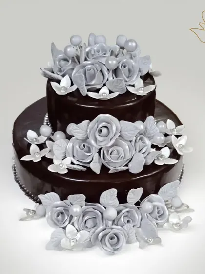 This two-tier chocolate cake is a masterpiece of taste and elegance. The deep, dark chocolate ganache is beautifully contrasted with handcrafted silver roses, making it perfect for a sophisticated anniversary or birthday.
