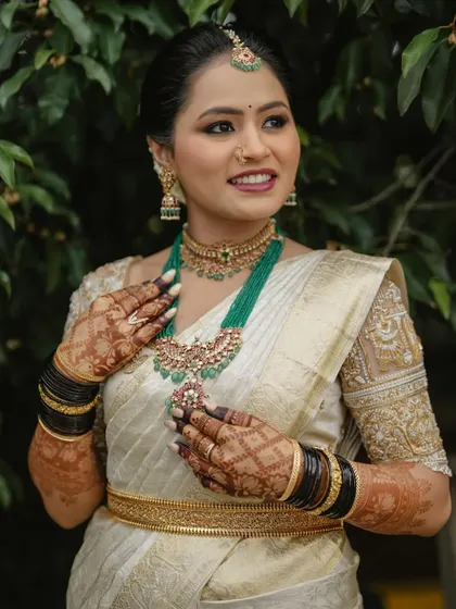 A close-up of Harshitha's radiant smile and the detailed henna on her hands.