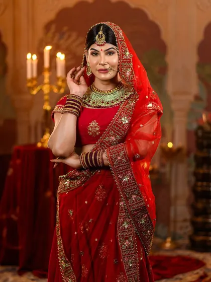 This pose showcases the rich texture and embroidery of the red velvet blouse and the sheer, embellished dupatta. Our styling ensures a look of authentic royal grace from every angle.