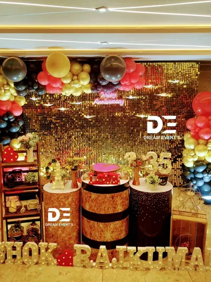 A glamorous 35th-anniversary party featuring a stunning gold sequin backdrop, a 'Happy Anniversary' neon sign, and a bold red, black, and gold balloon arrangement.