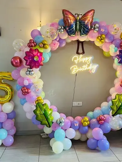 This butterfly garden theme is perfect for a whimsical birthday party. I created a full balloon ring in pastel colors, decorated with flower and butterfly foil balloons, and a 'Happy Birthday' neon sign.