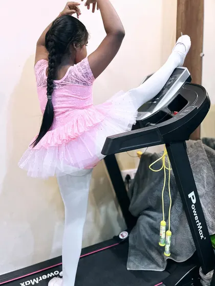 Another view of a student practicing a standing split with the help of a treadmill.