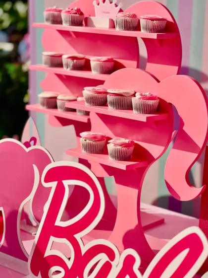 A custom-made Barbie silhouette shelf used to display pink-frosted cupcakes, adding a creative and functional decor element.