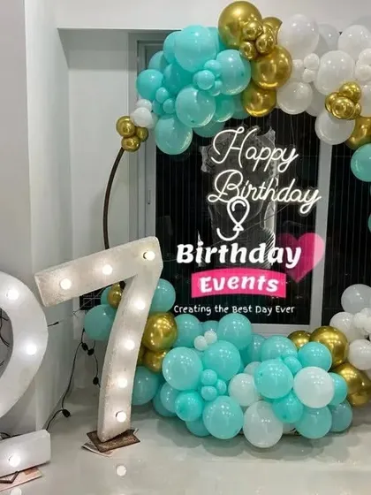 A vibrant and modern take on the ring backdrop, using a striking combination of turquoise, white, and gold chrome balloons. The large marquee numbers for the 27th birthday add a major statement piece.