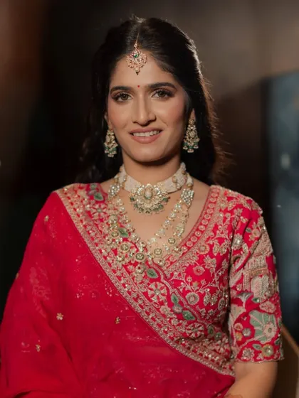 The finished look, a classic Indian bride with a red bindi, soft smokey eyes, and a radiant smile.