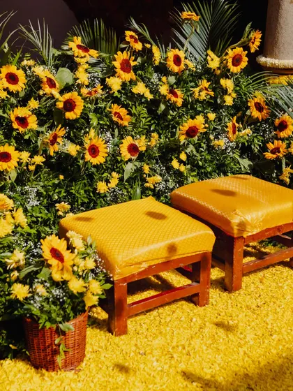 A close-up of the seating area for the couple at the Haldi ceremony, surrounded by a lush arrangement of sunflowers and a carpet of yellow petals.