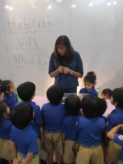 An instructor presents the 'Habitats' project to an eager group of young learners, who are gathered around to see what they will be creating.