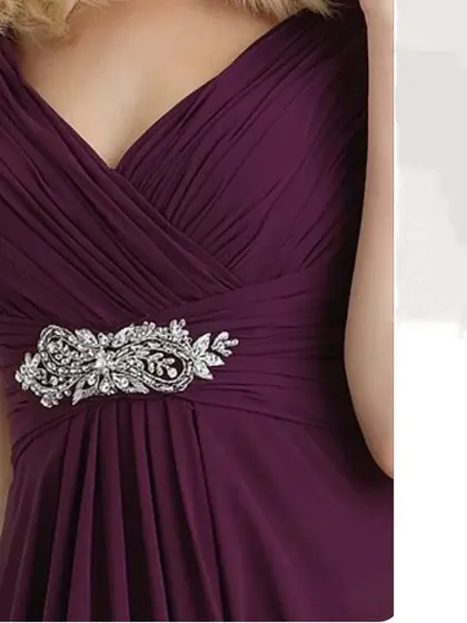 A close up of the crystal embellishment on one of our pleated purple gowns, adding a touch of sparkle.