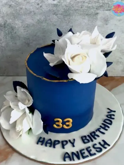 A sophisticated navy blue cake for Aneesh's 33rd birthday, adorned with beautiful white sugar flowers.