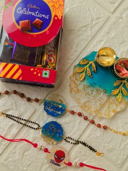 A beautiful Rakhi hamper featuring a resin thali, chocolates, and a set of three unique rakhis for the whole family.