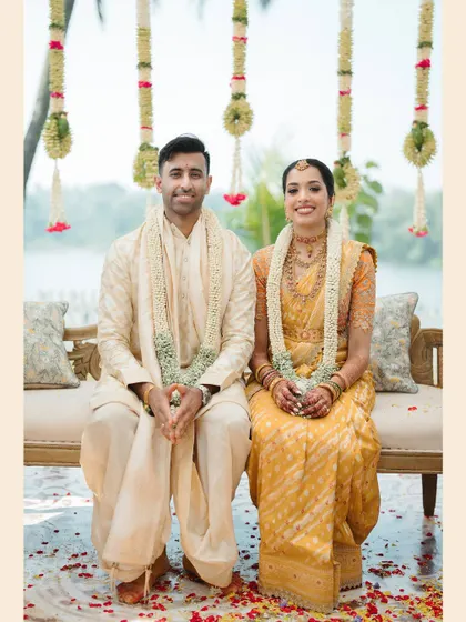 A classic portrait of the couple seated at their wedding, dressed in beautiful traditional South Indian attire.