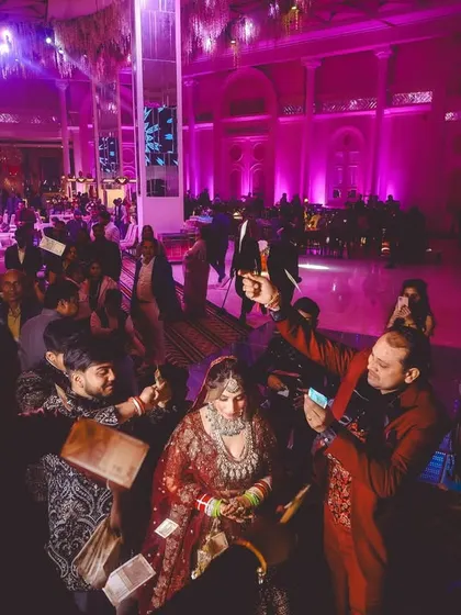 A wide-angle shot capturing the energy of the wedding, with guests surrounding the bride to take photos.