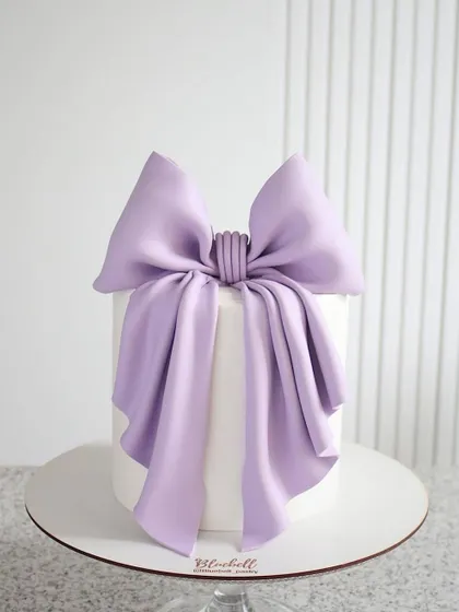A simple yet stunning white cake with a perfectly draped lavender bow. This minimalist design shows the power of a single, well-executed element.