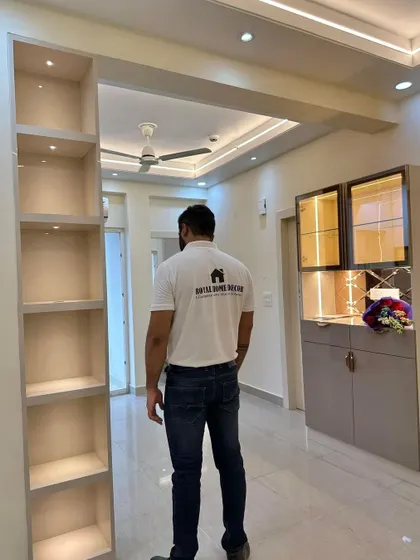 A look at a completed living area, showing a stylish crockery unit with glass doors and a partition with built-in shelves, demonstrating our expertise in creating custom storage solutions.
