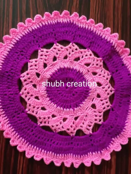A round crochet doily with a layered design in two shades of pink, creating depth and texture.