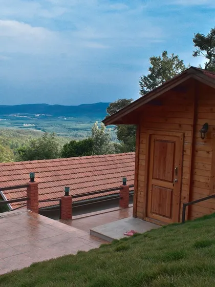 A wooden cabin perched on a hill in Chikmagalur, with a spacious terrace offering expansive views of the valley below.
