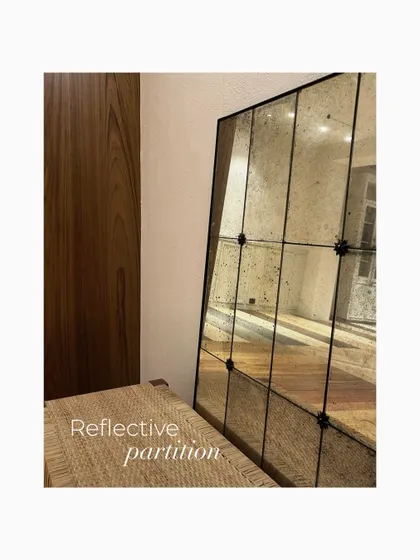 A reflective, antiqued mirror partition leaning against a wall during setup. This piece was chosen to add a sense of history and glamour, reflecting light and creating an illusion of expanded space.