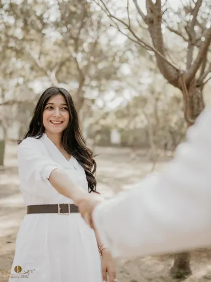 A "follow me" style shot where the woman leads her partner through a sunlit grove. Her bright smile captures the joy and excitement of their journey together.