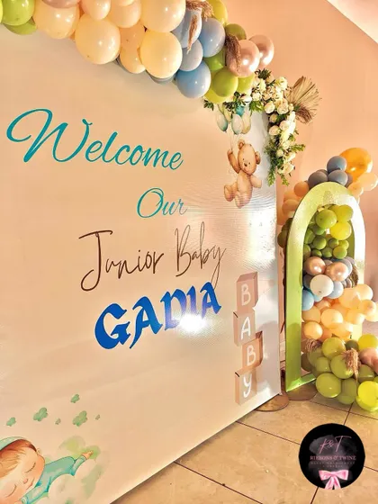 A close-up of the personalized backdrop for the baby welcome party, showing the custom text and cute teddy bear graphic.