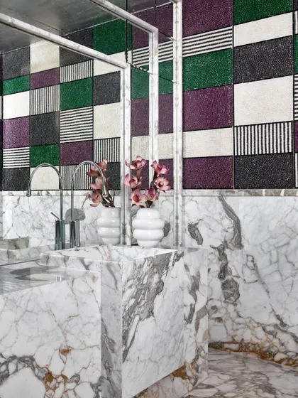 A powder room in the Ventura gallery that showcases a bold approach to materials. I contrasted the organic, heavy veins of the marble vanity with graphic, multi-patterned mosaic tiles on the wall. It's an example of how I use unexpected combinations to create visual interest and a sense of quiet luxury.