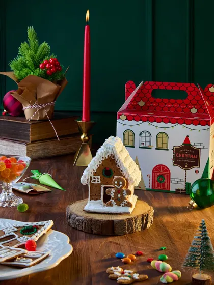 A whimsical shot focusing on a DIY gingerbread house from the Marriott Bonvoy Christmas collection. The warm, woody tones and festive decorations create a magical, storybook feel that appeals to families.