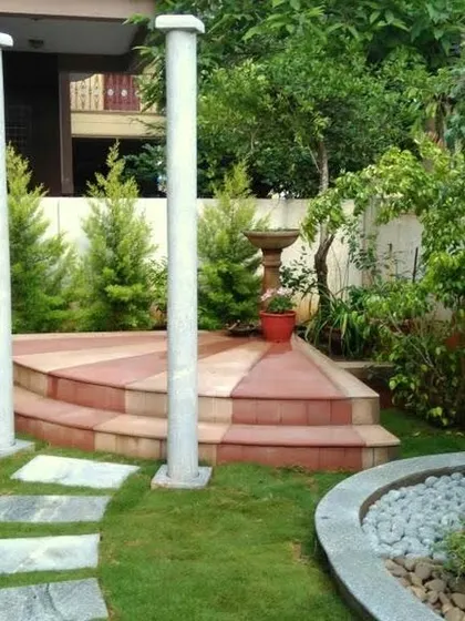 An elegant garden stage area with stone pillars and tiered steps, perfect for placing sculptures or creating a performance space within the landscape.