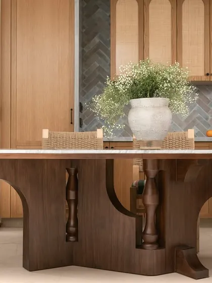 A view of the dining area in Kolam Pop, featuring a bold, curvilinear table base with lathe-turned accents. The mix of woven textures and striped upholstery brings a touch of nostalgia and craft.