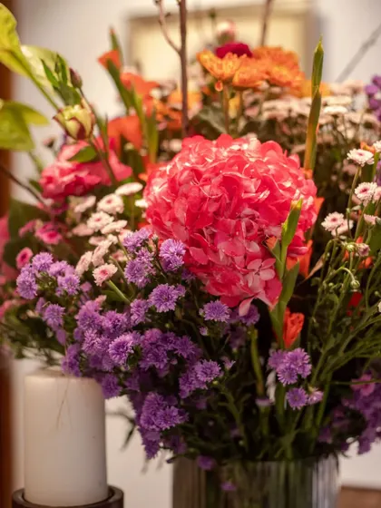 A detail shot showing the mix of pink hydrangeas and purple statice. The combination of soft and sharp textures adds depth and interest to the arrangement.