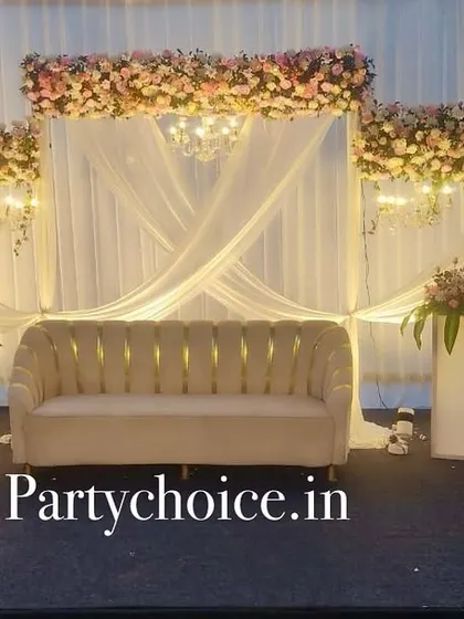 An elegant outdoor engagement stage at dusk. The white drapes, floral headers, and chandeliers create a magical and romantic atmosphere.