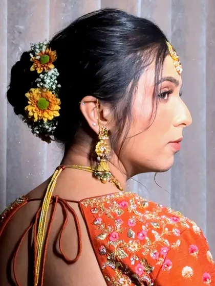 A side view of a classic bridal bun, adorned with fresh yellow and white flowers.