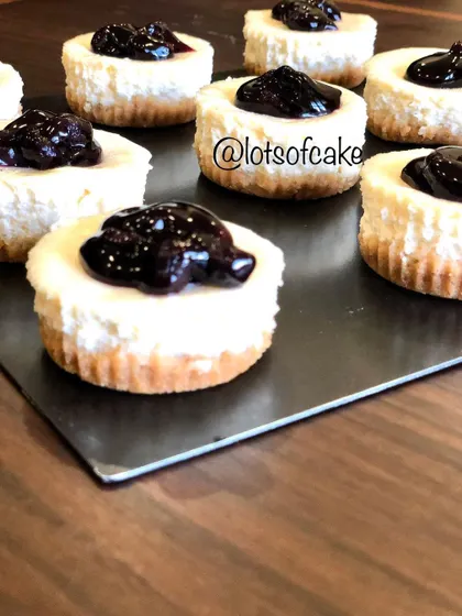 A close-up of the mini blueberry cheesecakes, showing the texture of the baked cheesecake and the glossy topping.
