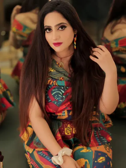 A close-up portrait that captures the model's direct gaze and the vibrant colors of her makeup and outfit.